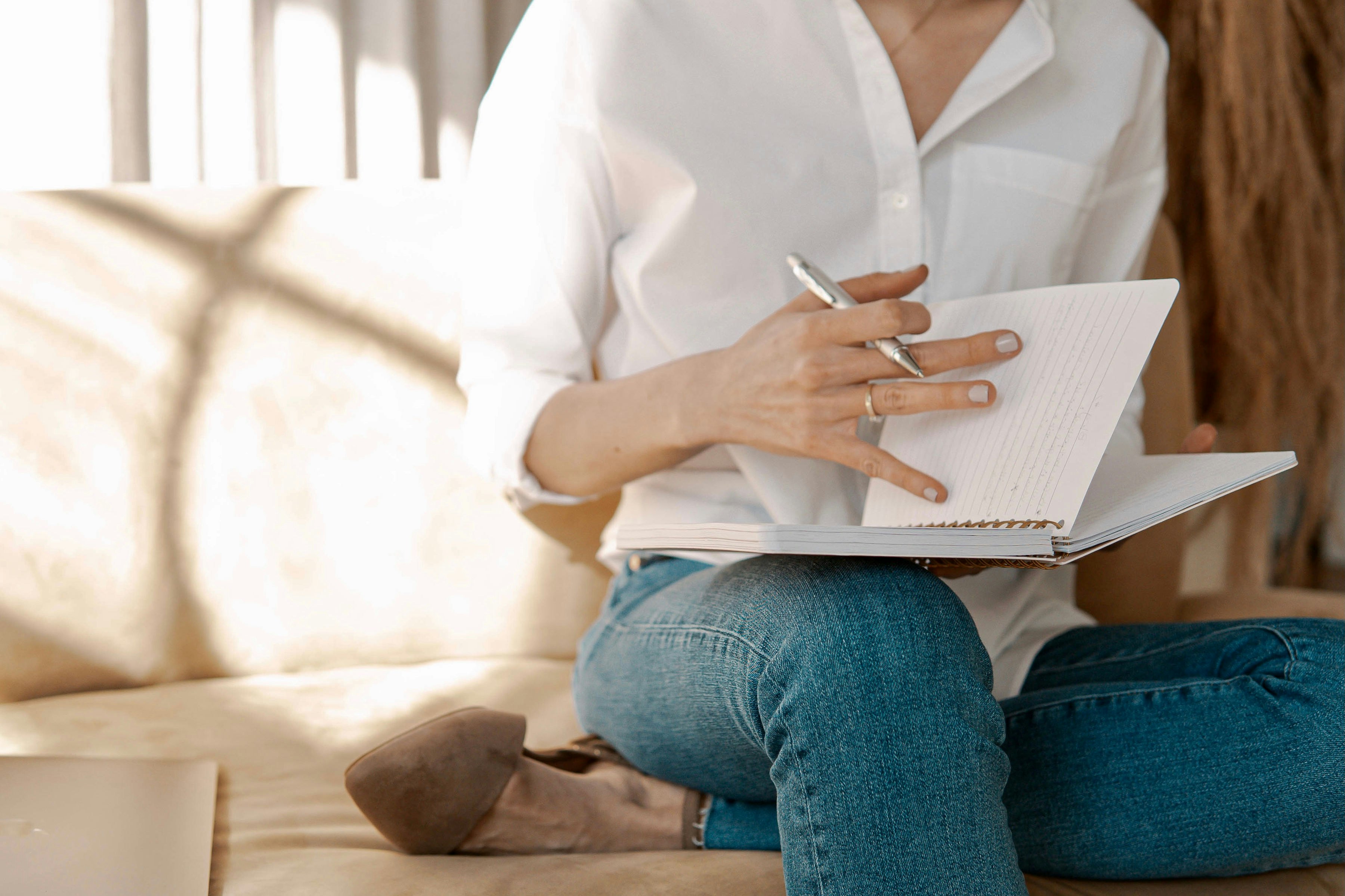 man in white dress shirt and blue denim jeans sitting on brown sand